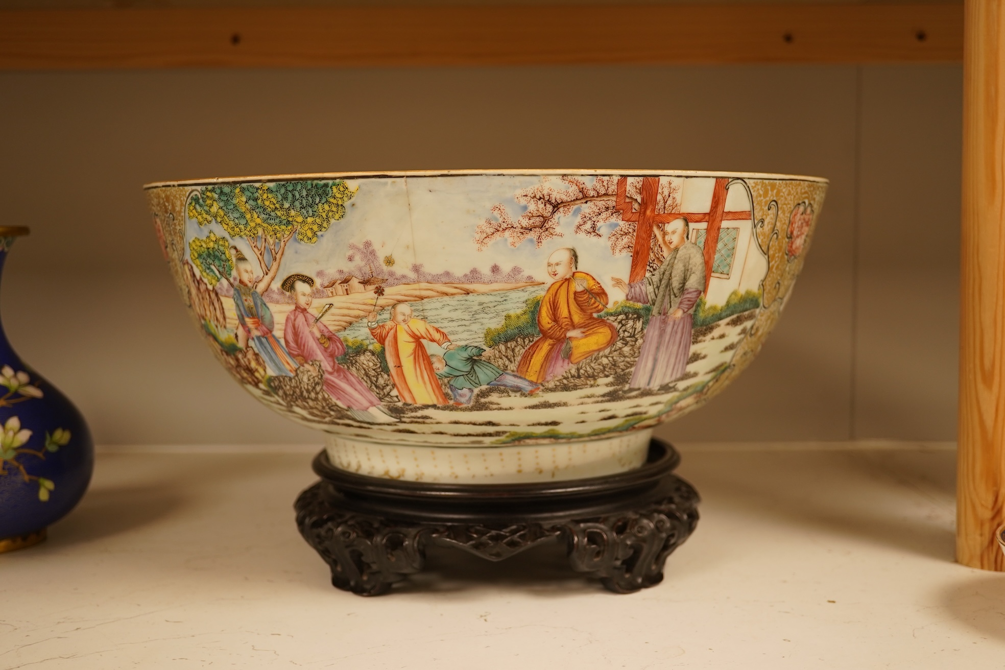 An 18th century Chinese famille rose figural bowl, on wooden stand, 34cm diameter.